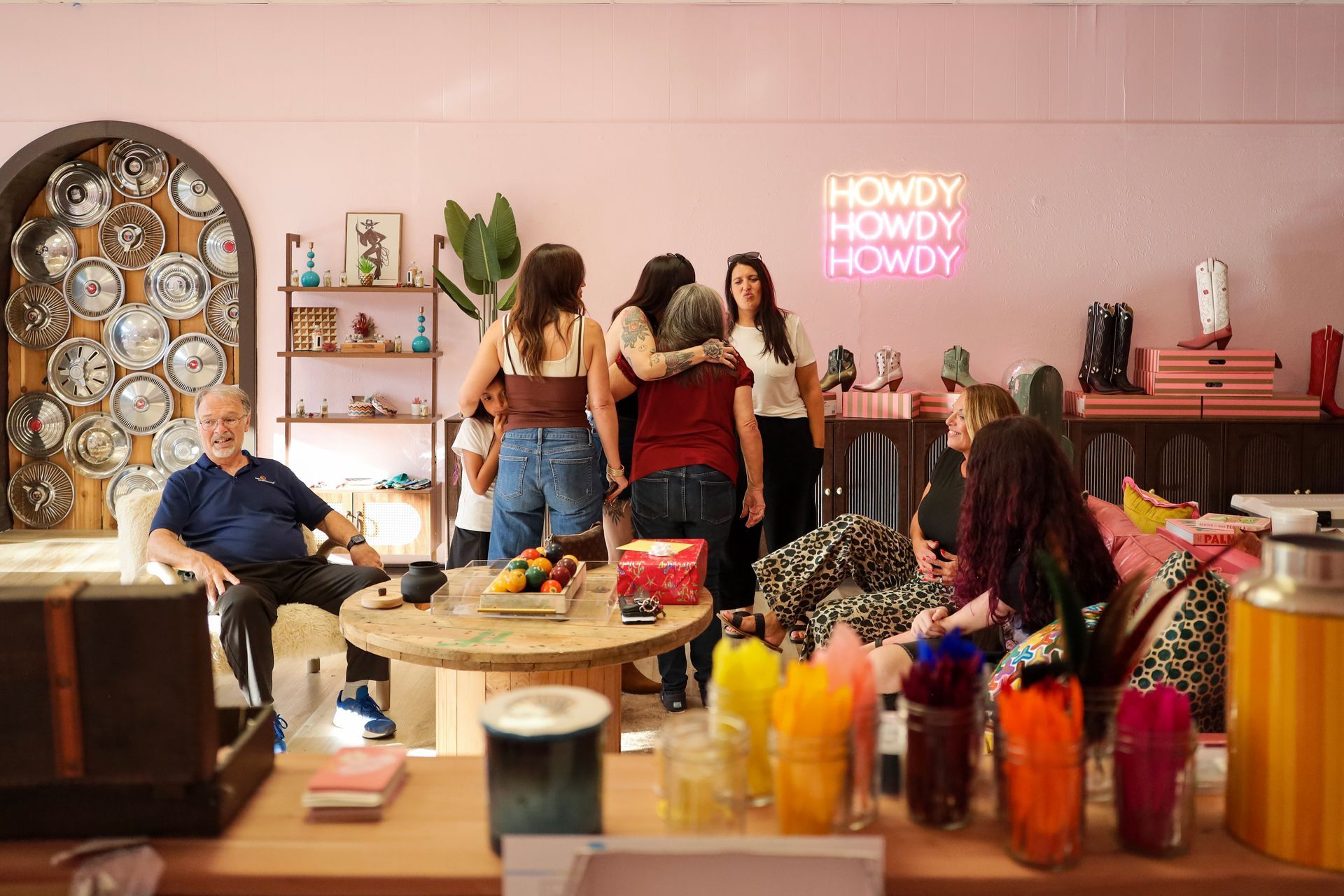 Group chatting in a pink lounge with drinks and bottles on a table