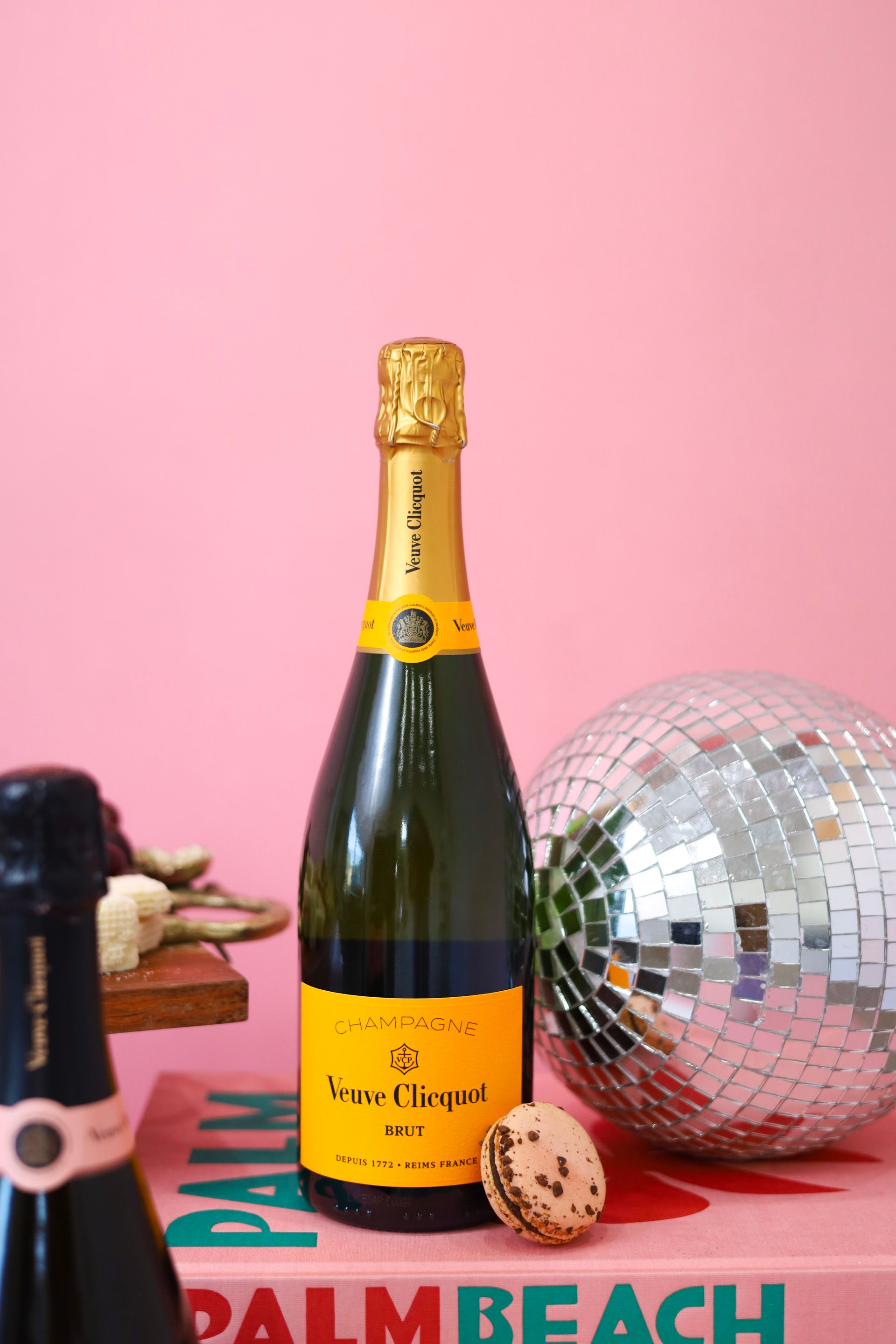 Champagne bottle with disco ball on pink backdrop, styled for a Palm Beach party scene