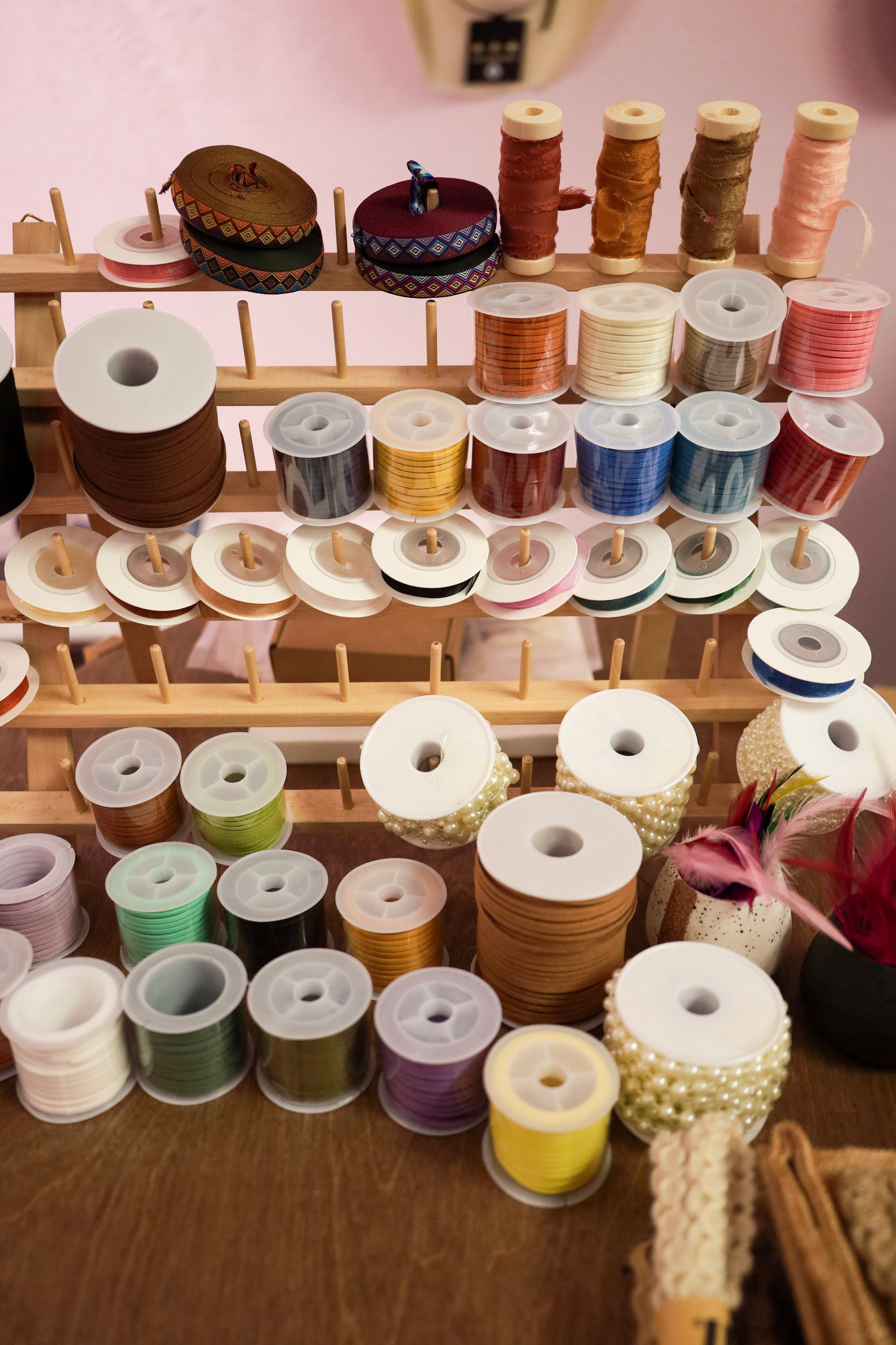 Shelves of assorted sewing thread spools in white, pink, blue, and brown tones