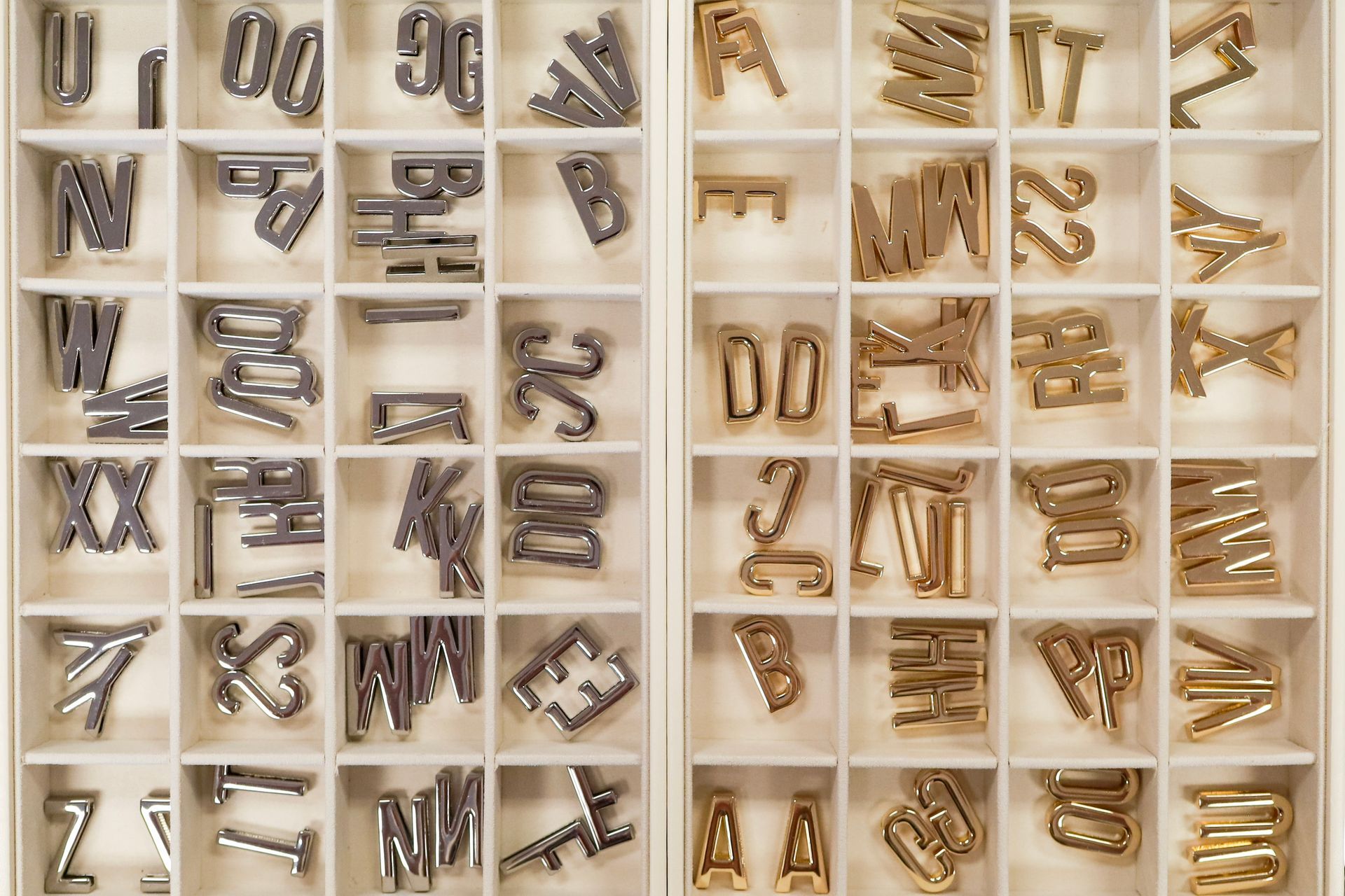 Assorted metal alphabet and number stamps organized in a compartmented tray