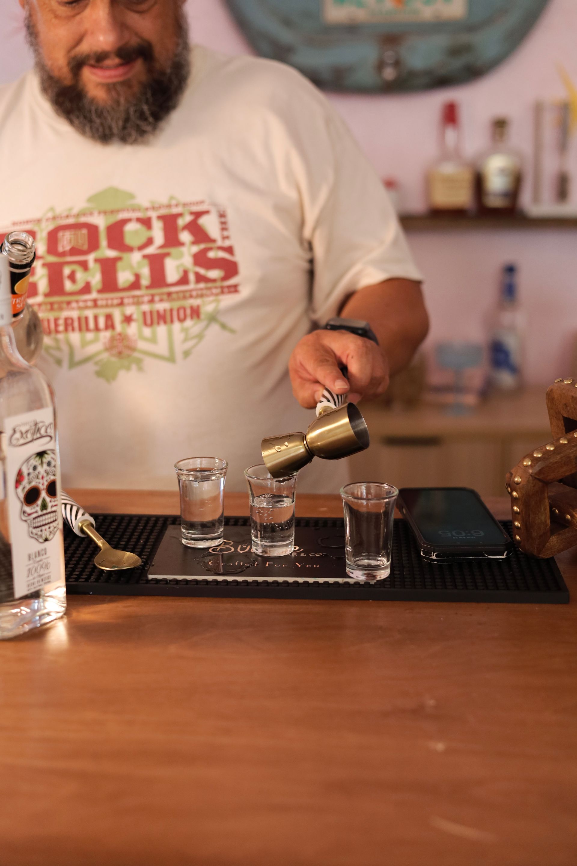 Bartender pouring a drink into a shot glass behind a bar counter