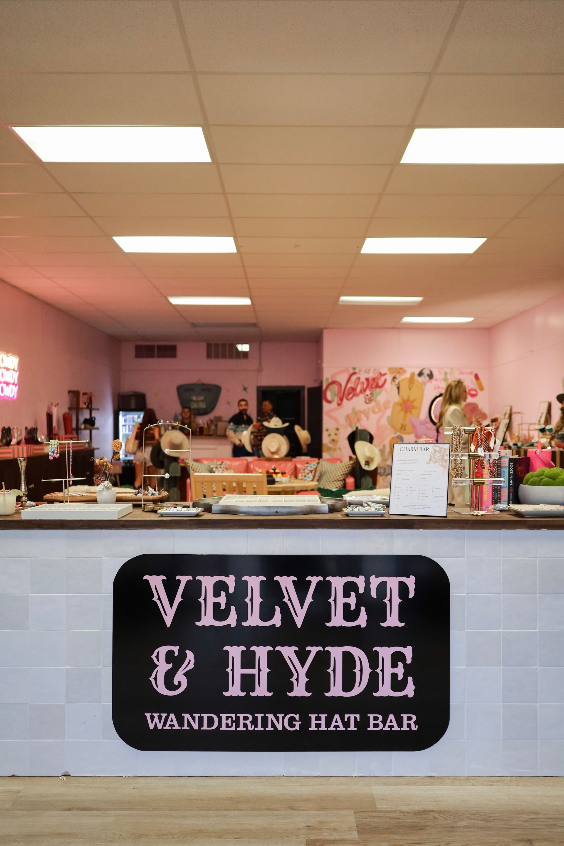 Pink bar interior with a counter sign reading “Velvet & Hyde Wandering Bar”