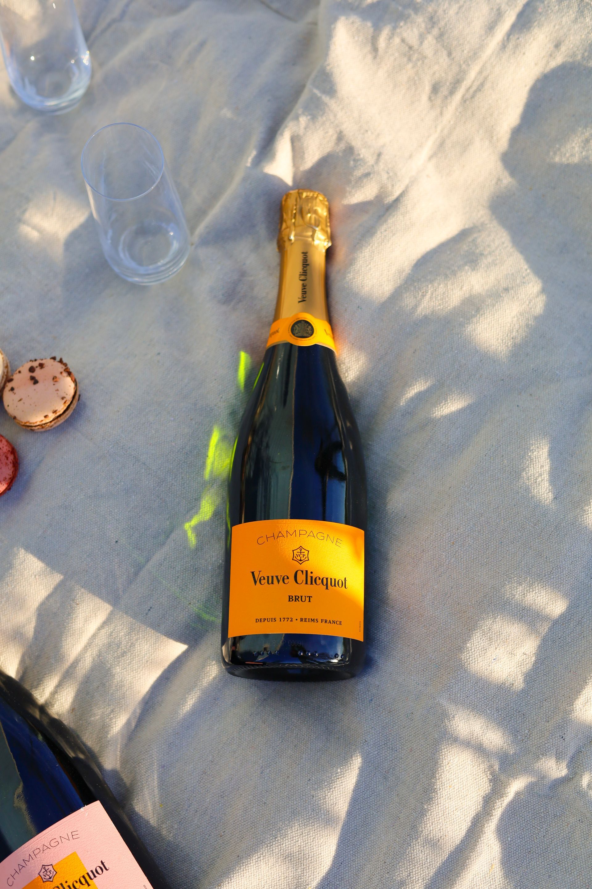 Bottle of champagne on a sandy cloth, with a glass and cork nearby.