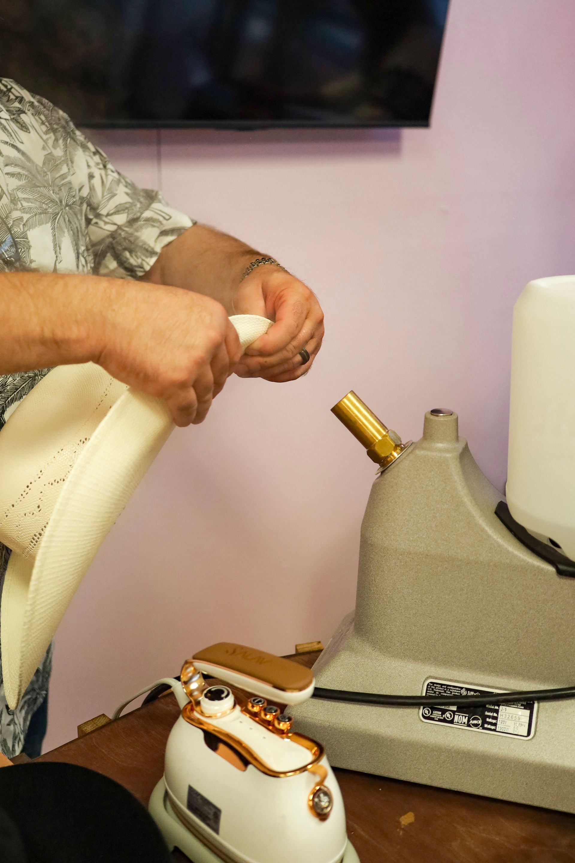 Hands adjusting a white chair near a sewing machine on a table with fabric and tools