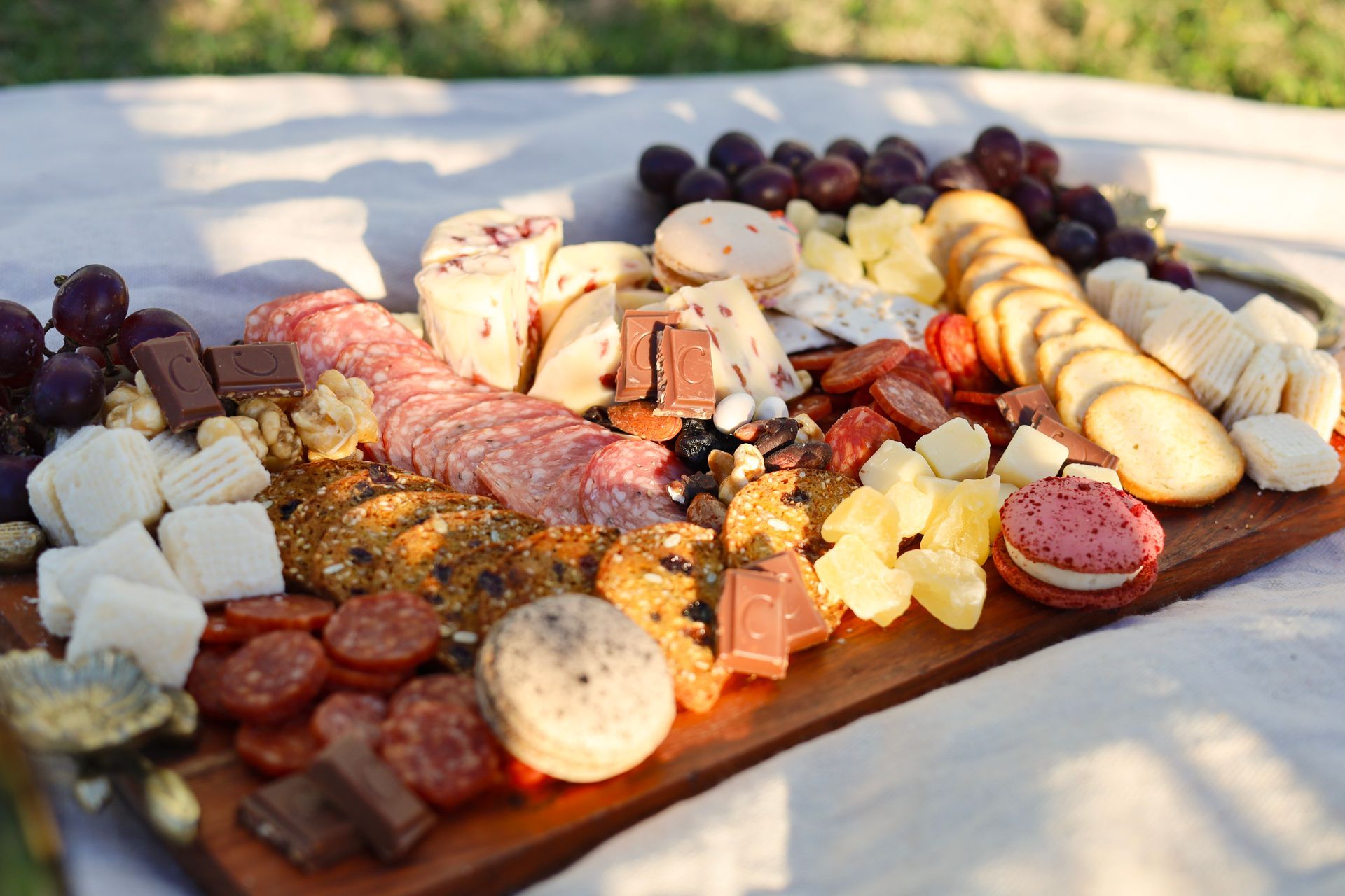 Charcuterie board with cheeses, cured meats, fruit, crackers, and bread on an outdoor table