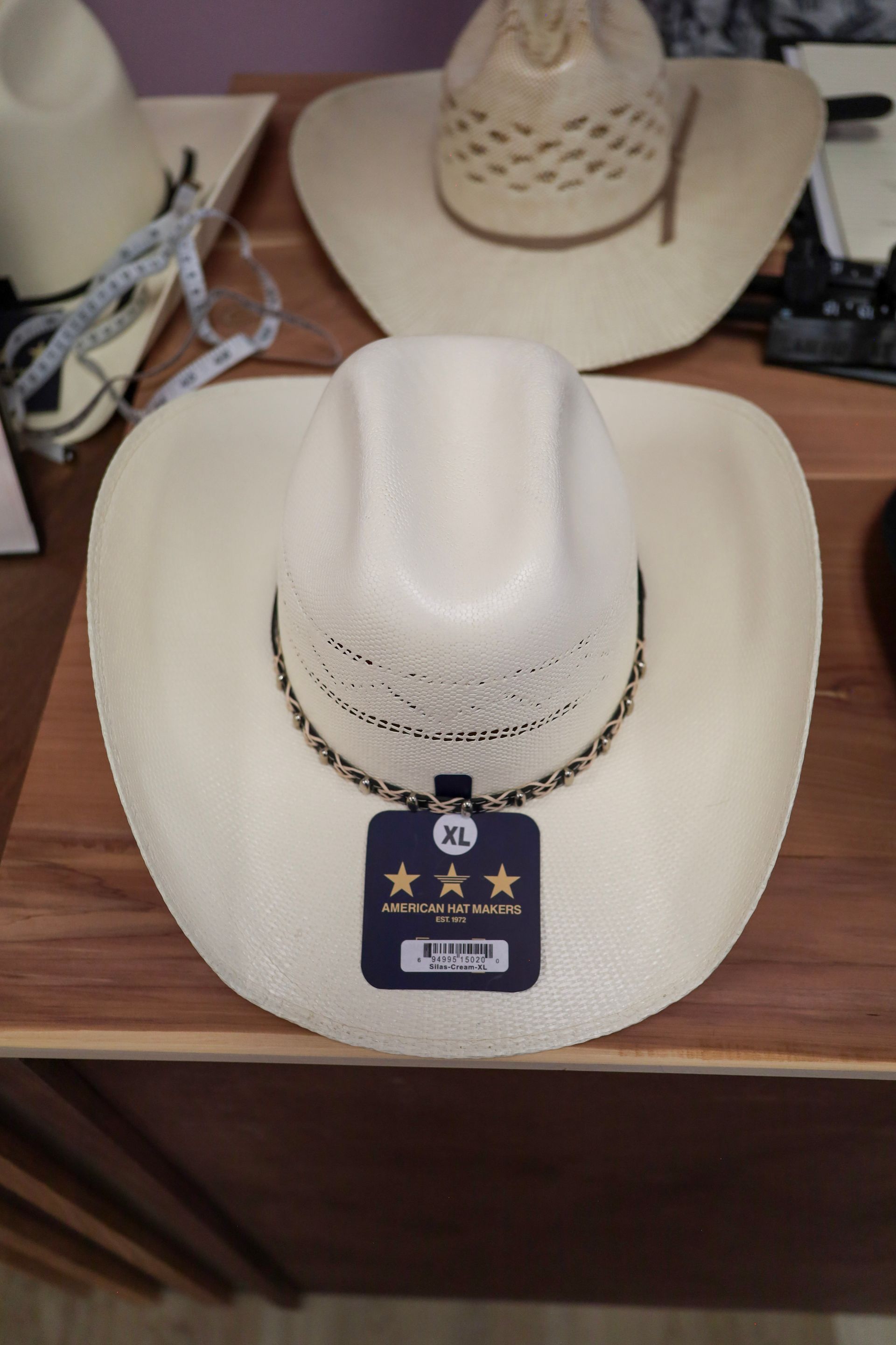 White cowboy hat on a display stand with a blue price tag and chain necklace, on a shelf