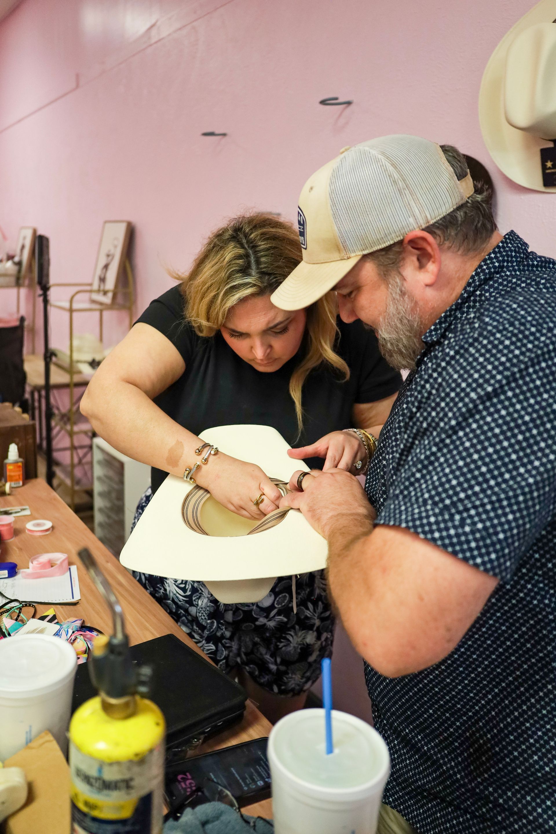 Two people working together on a craft project at a table, shaping a white object.