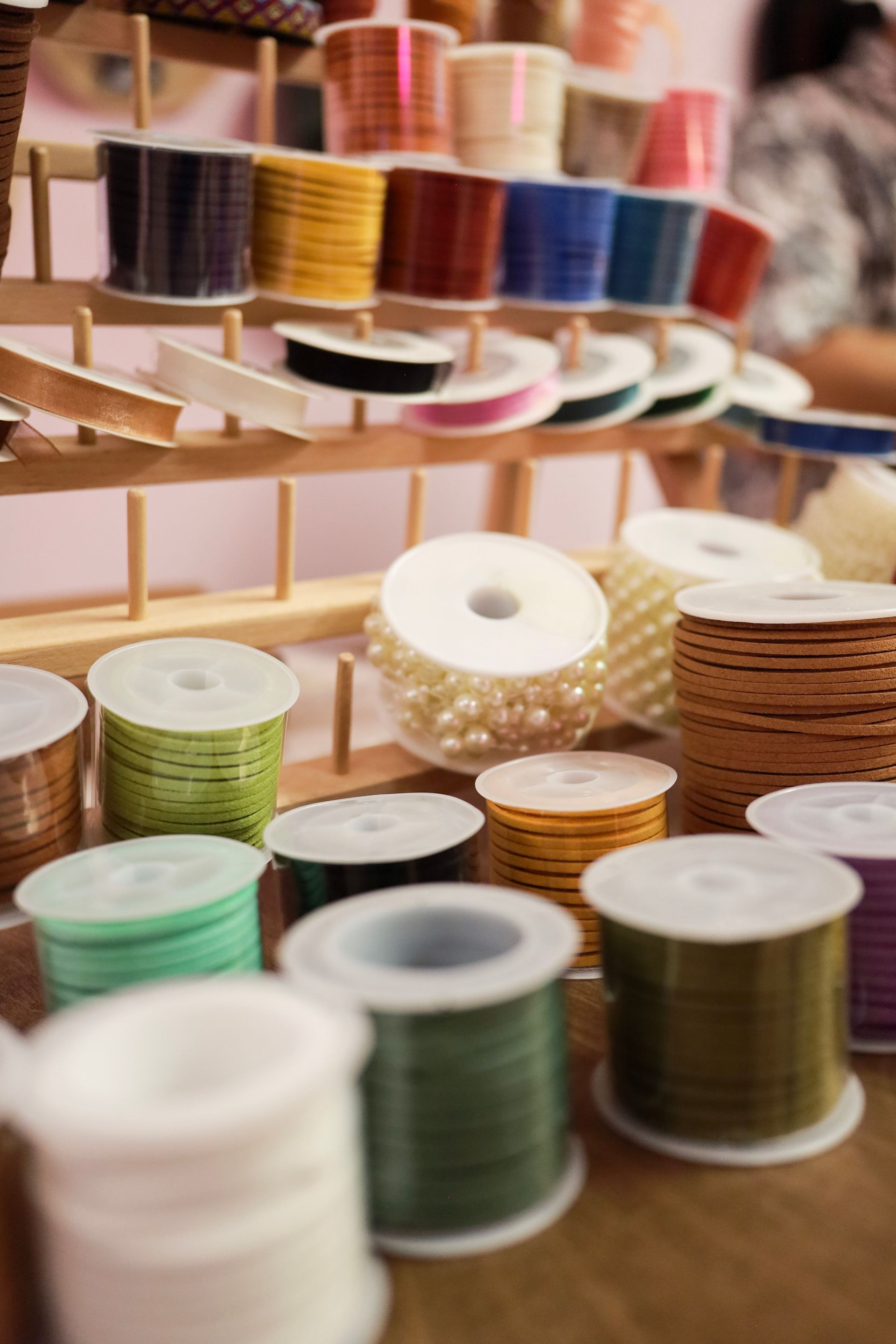 Rows of colorful thread spools stacked on wooden shelves in a craft store