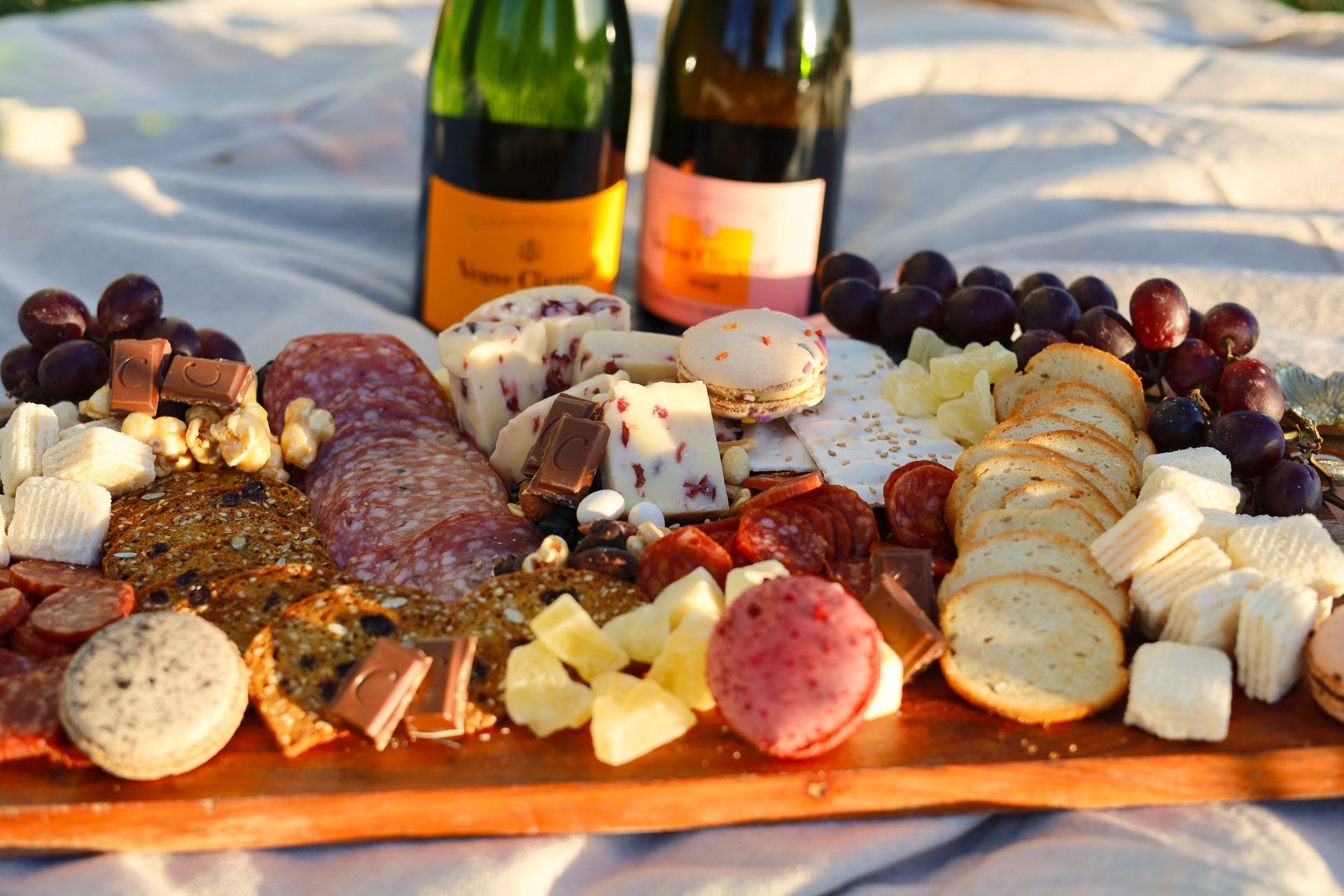 Charcuterie platter with cheeses, meats, crackers, grapes, and wine on a table outdoors