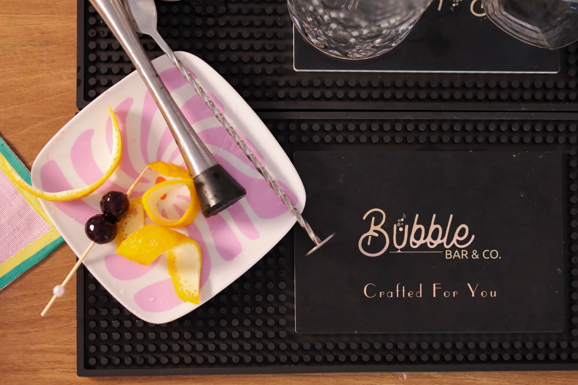 Cocktail tray with pink and yellow citrus peels on a Bubble Bar & Co. black mat