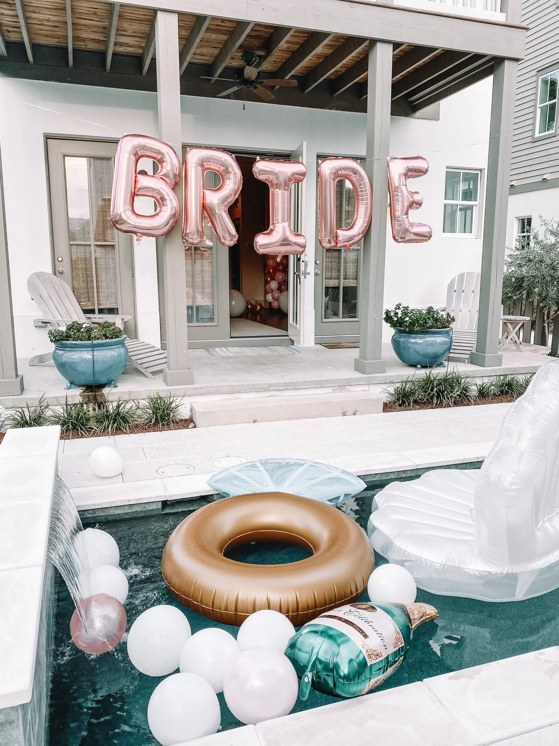 Bride balloon sign at a decorated porch poolside party with pink, gold, and white floats