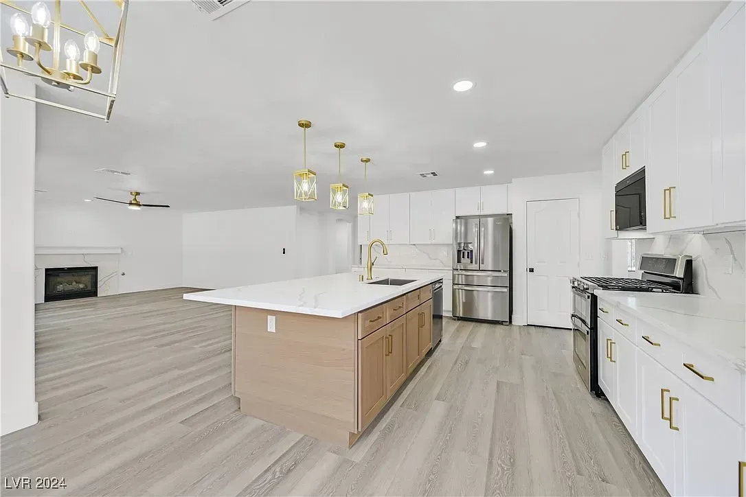 Bright modern kitchen with white cabinets, large island, stainless steel appliances, and light wood floors