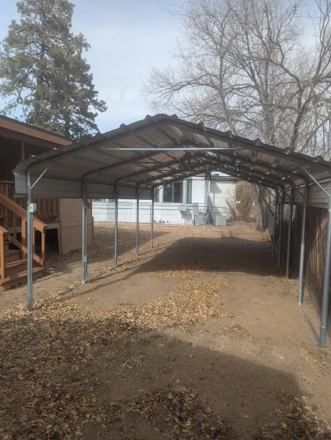 There is a carport in the backyard of a house.