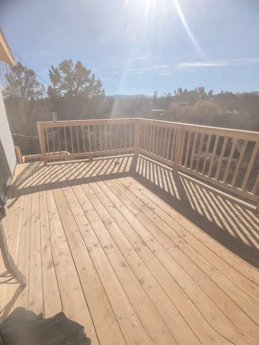 A wooden deck with a railing on a sunny day.