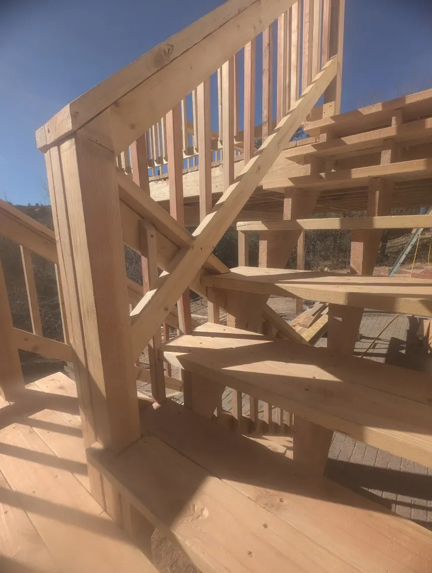 A wooden staircase is being built in a house under construction.