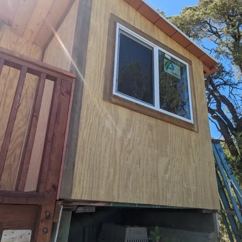 A wooden house with two windows and a balcony