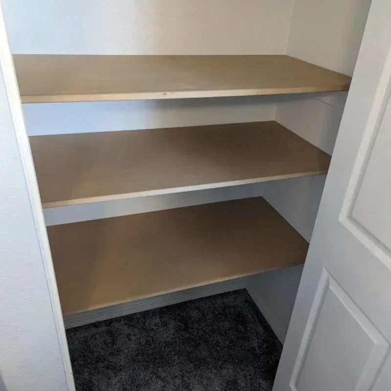 A closet with three shelves and a white door