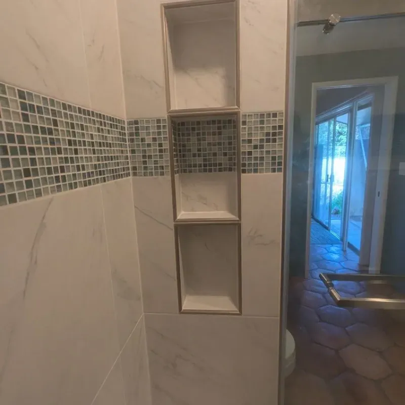 A bathroom with a shower stall and a shelf in the wall.