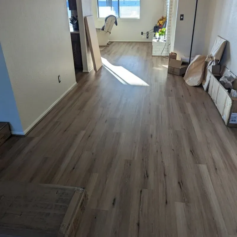 A living room with hardwood floors and boxes on the floor.