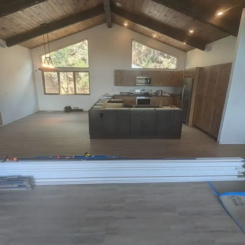 A large room with a couch and a kitchen in the background.