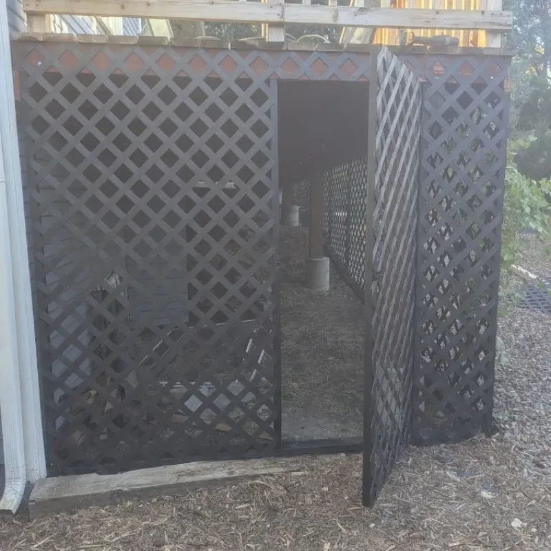 A black lattice fence with a door open