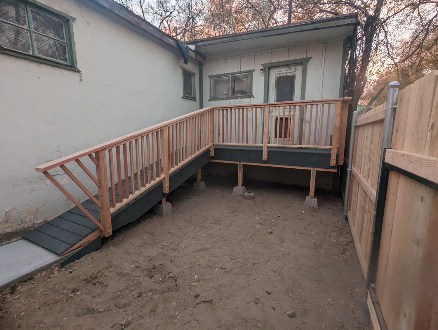 A wooden deck with a ramp in the backyard of a house