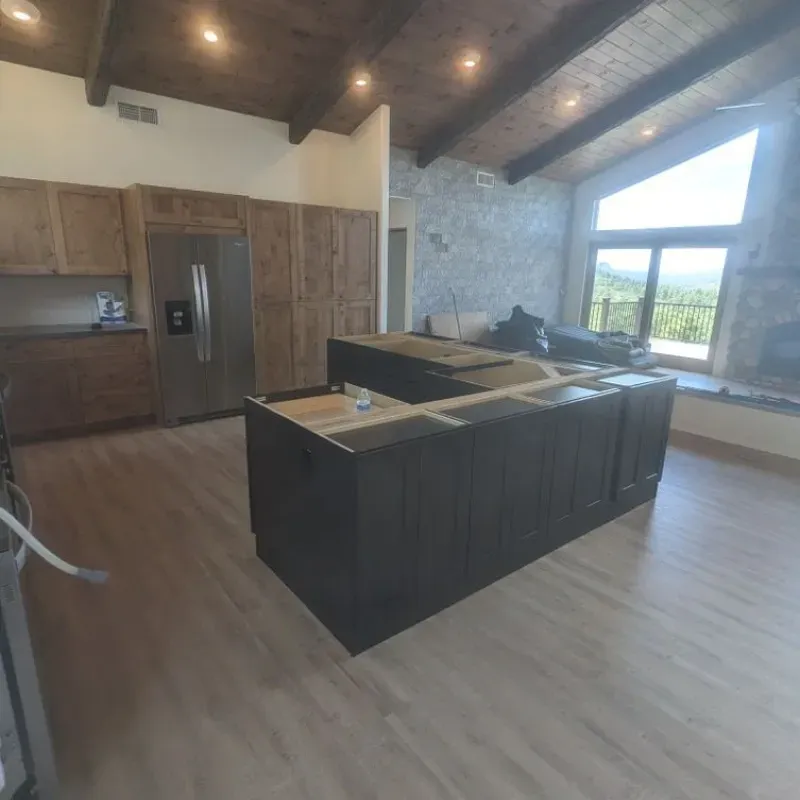 A kitchen with a large island and a stainless steel refrigerator