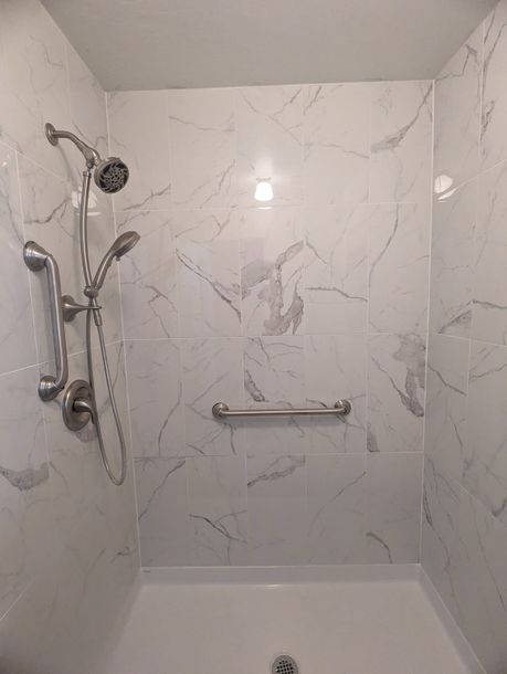 A shower with a hand rail and a shower head.