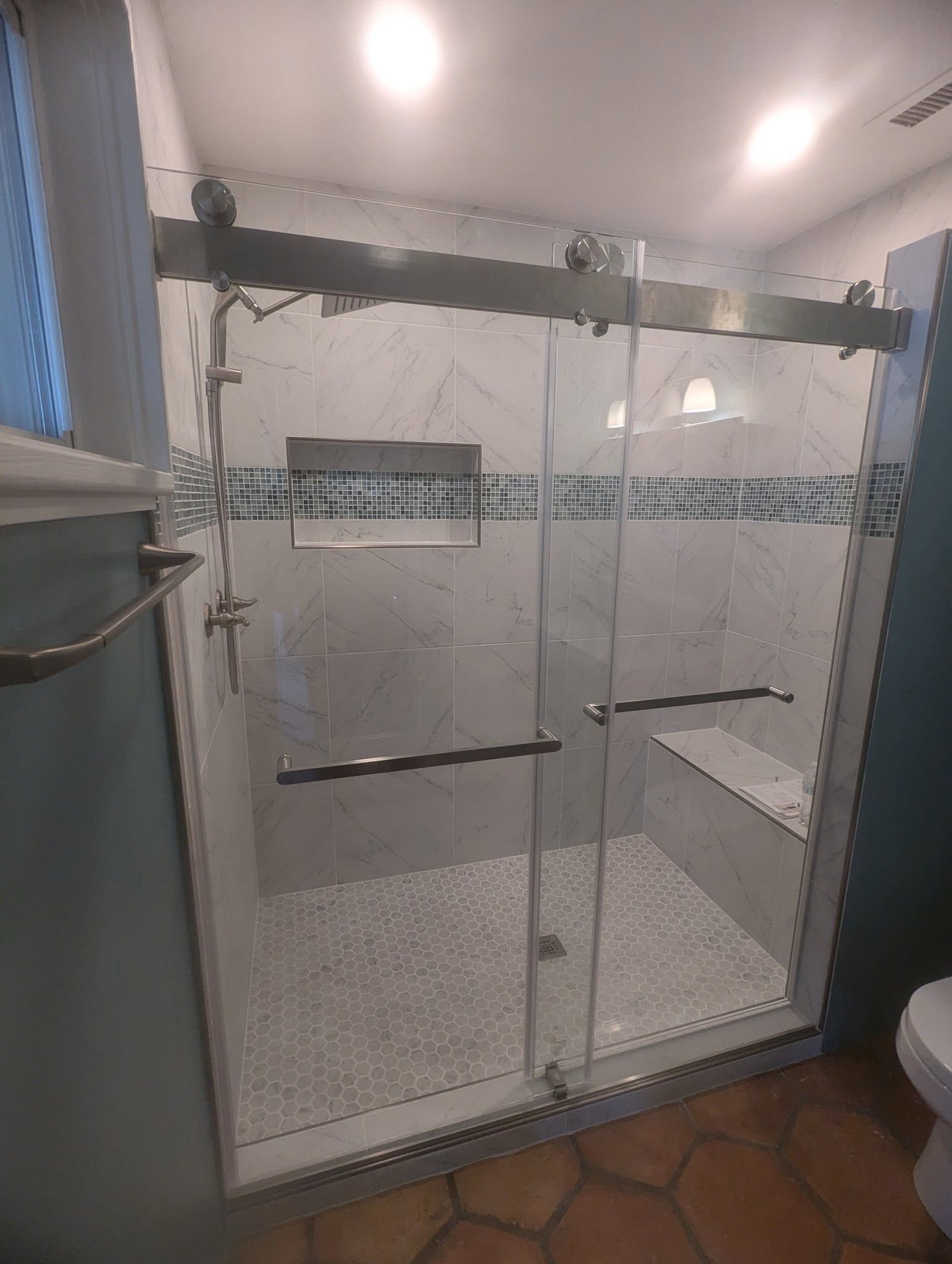 A bathroom with a sliding glass shower door and a toilet.