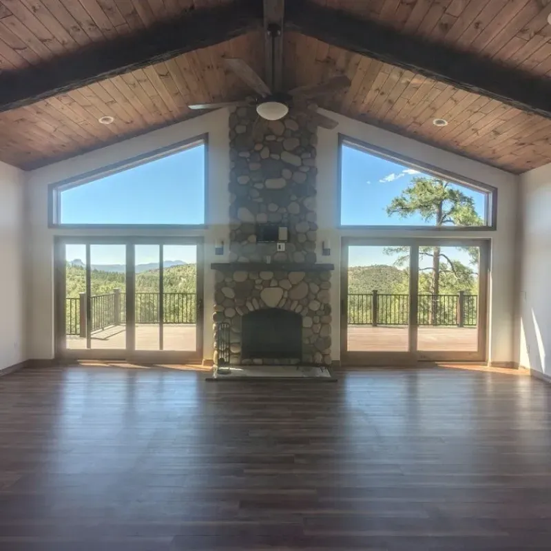 An empty living room with a fireplace and lots of windows