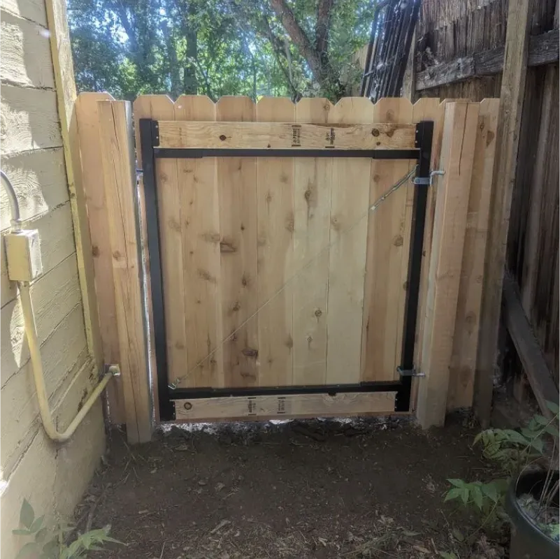 A wooden fence with a metal gate in the backyard