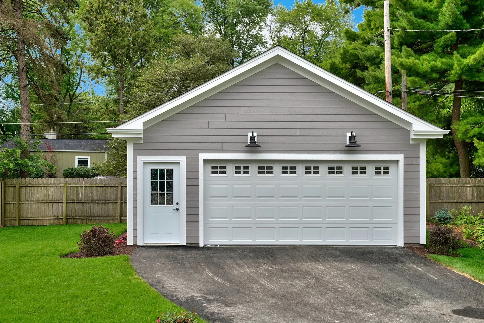 A garage with a white door and a driveway in front of a house.