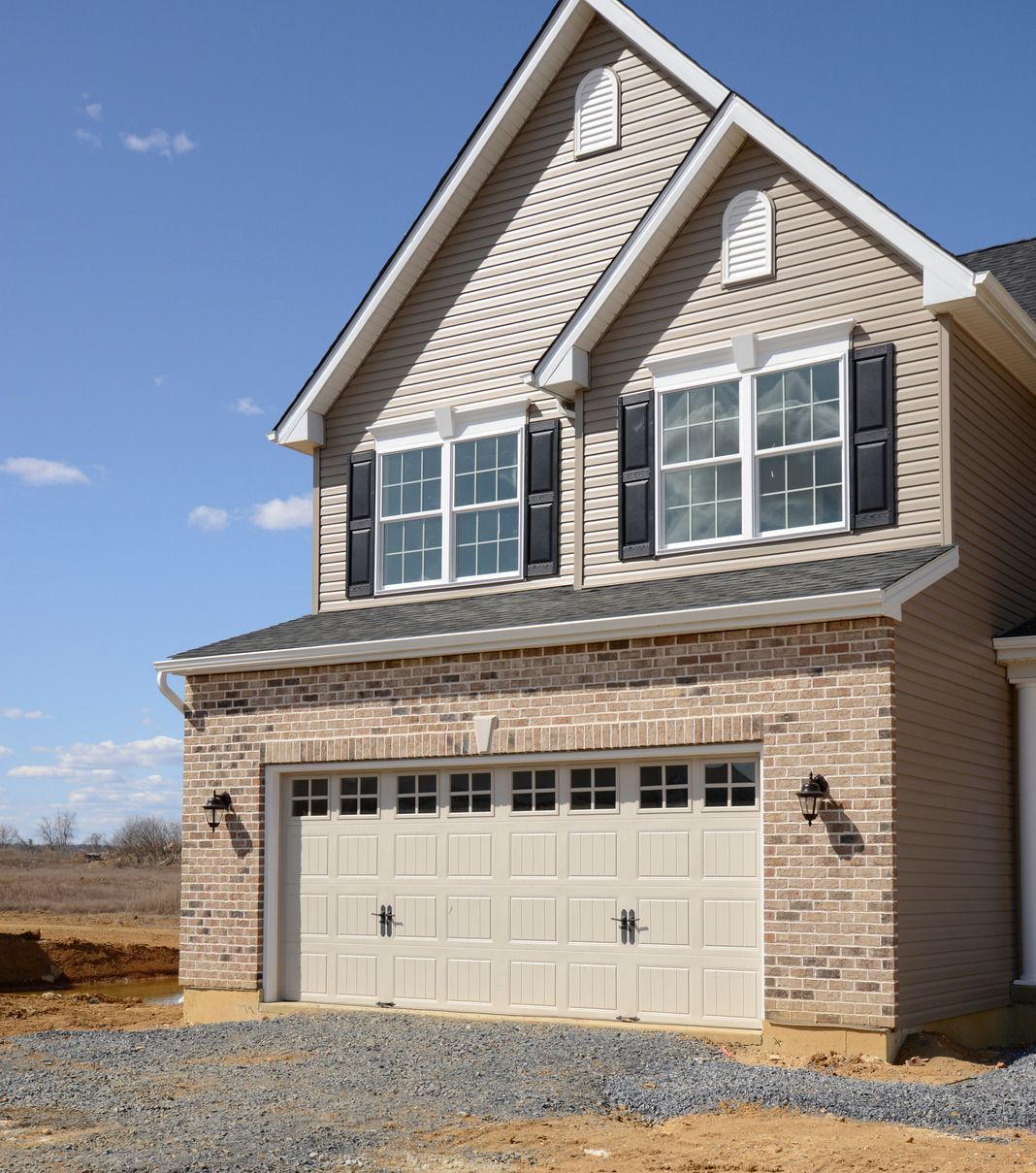 A brick house with a white garage door and black shutters