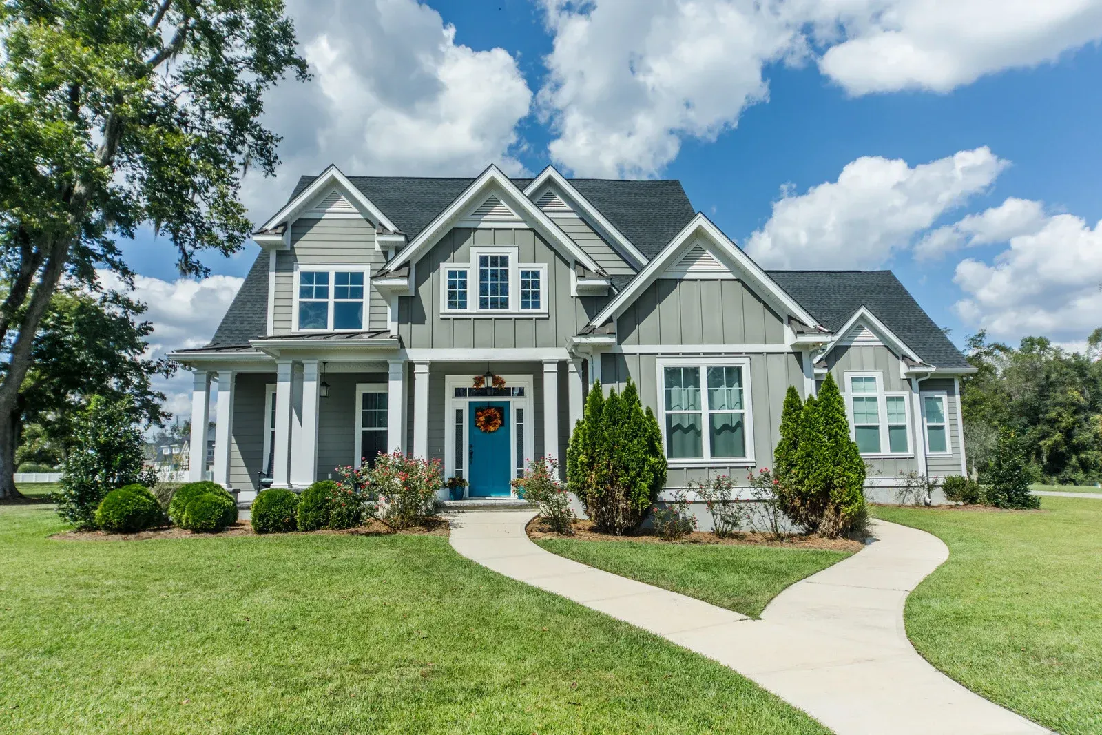 A large gray house with a blue door and a walkway leading to it.
