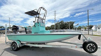 A light-green fishing boat on a trailer, under a sunny sky.