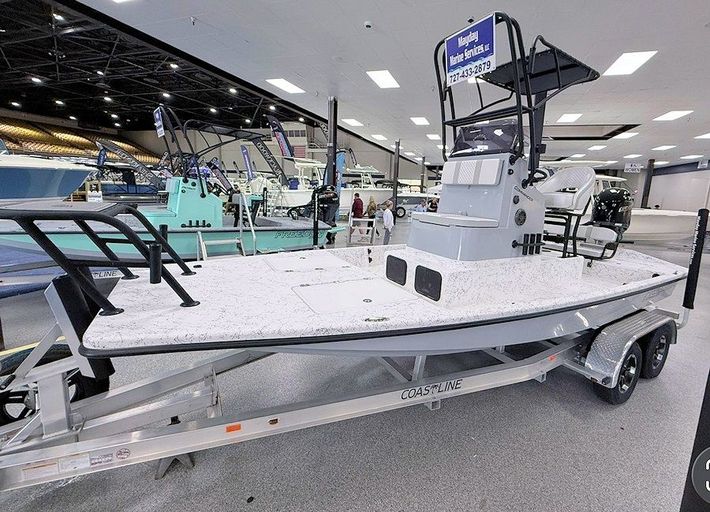 New 2026 Freedom Commander shallow water fishing boat on a trailer indoors at a boat showroom, with center console and T-top.