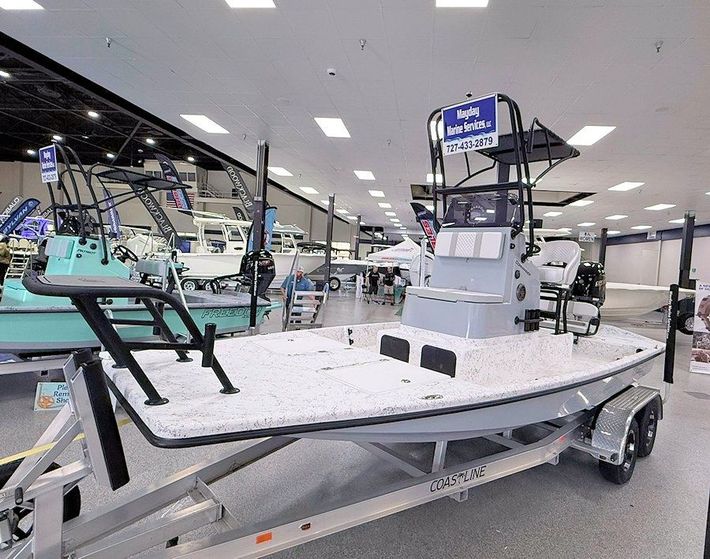 New 2026 Freedom Commander shallow water fishing boat on a trailer inside a bright showroom.