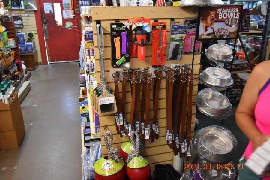 Store aisle with hanging tools and kitchenware, plus stacked pans and shopping baskets.