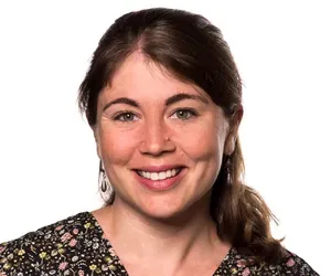 A woman in a floral shirt is smiling for the camera.
