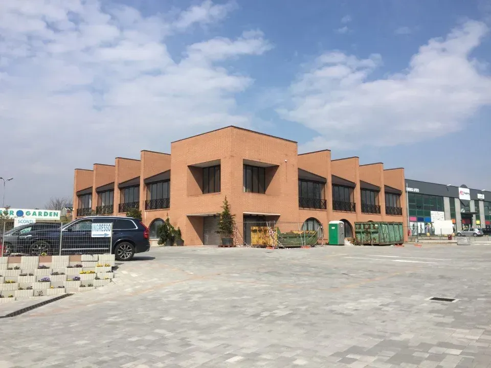 Un edificio a due piani in mattoni color pesca, con linee del tetto ritmiche e angolari, situato in un parcheggio asfaltato in una giornata di sole.