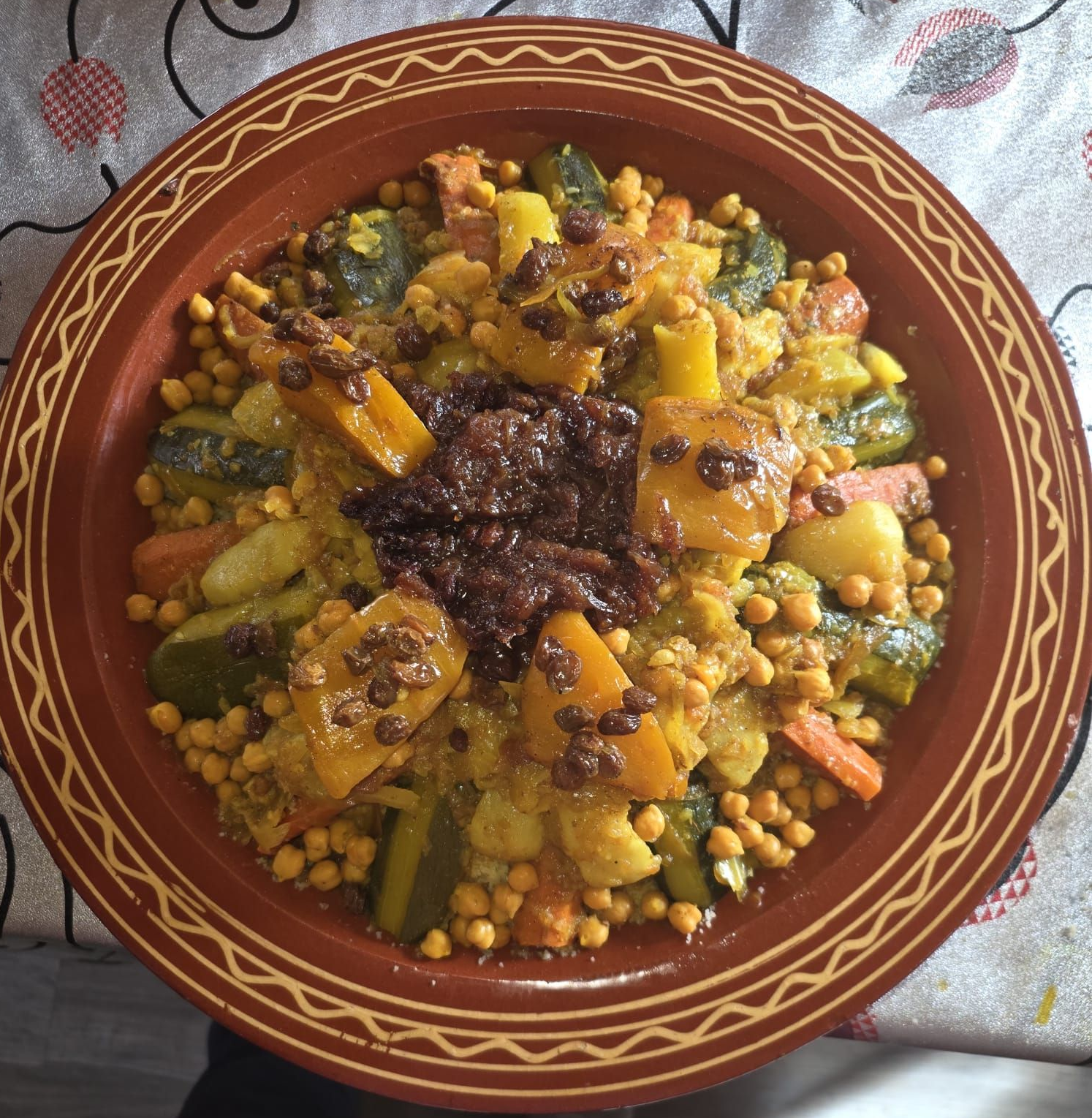 Couscous aux légumes variés et aux pois chiches, servi dans un bol en terre cuite.
