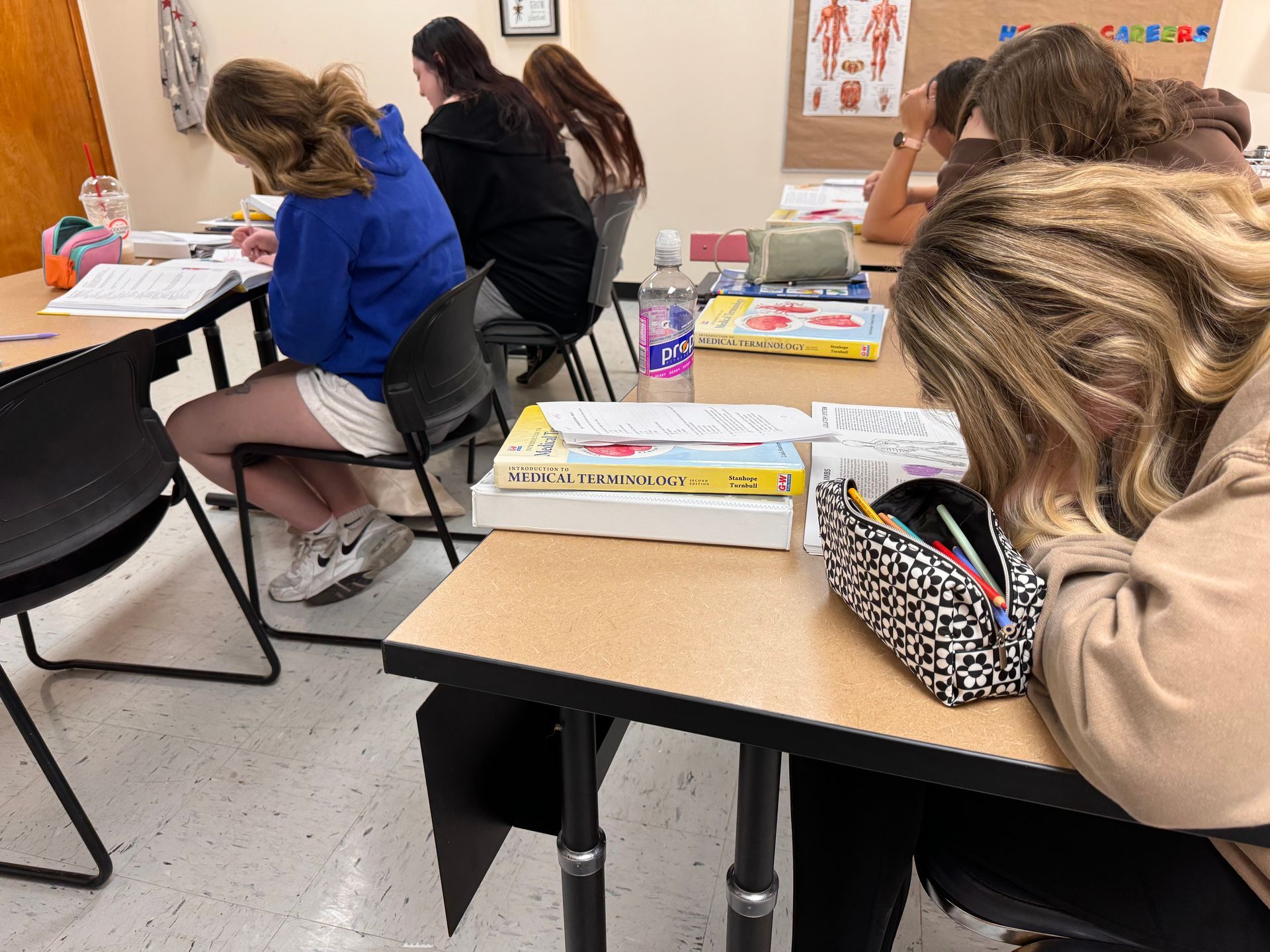 Students seated at classroom desks, writing and working quietly during class