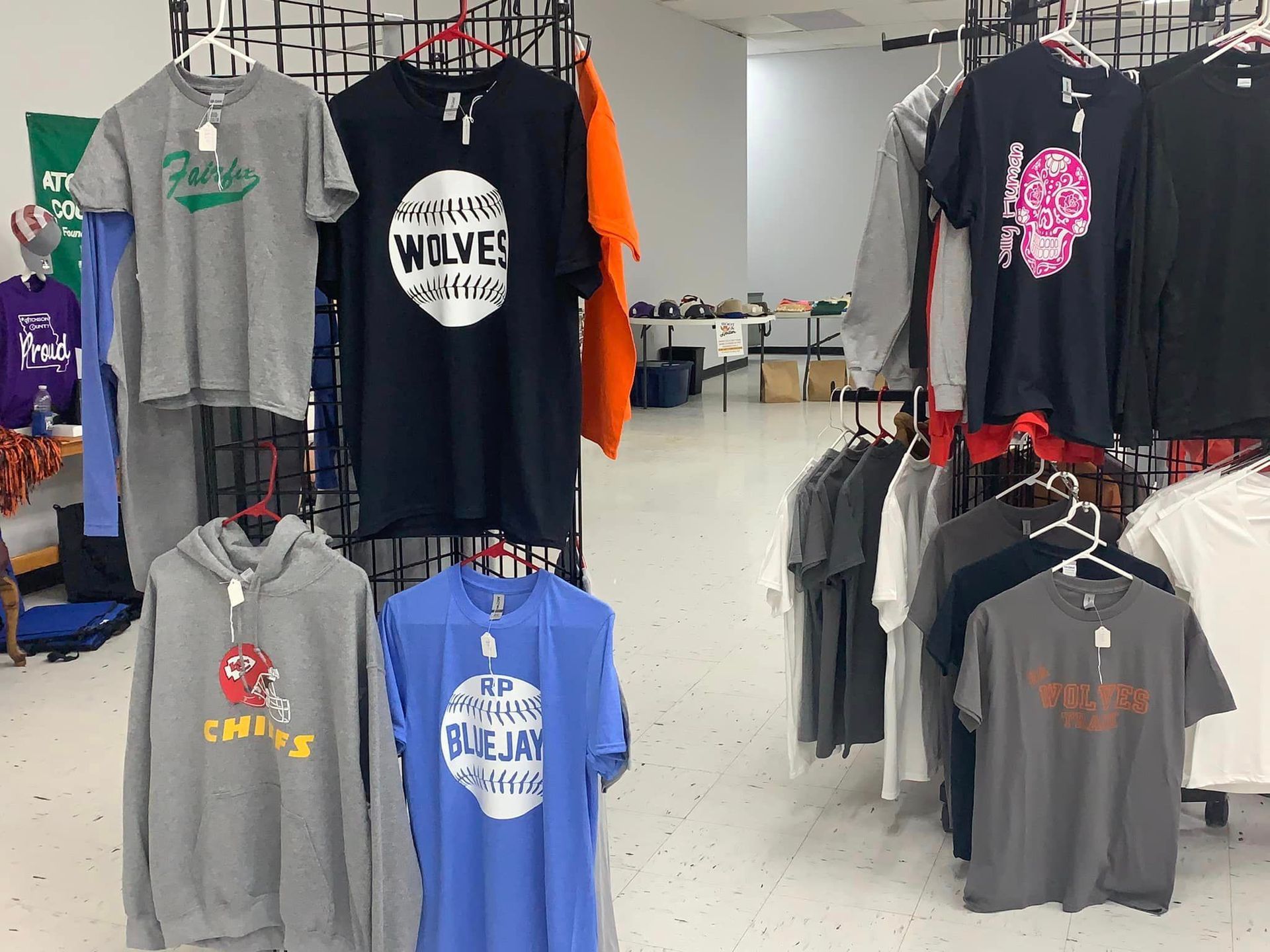 Clothing racks with assorted graphic T-shirts in a store aisle.