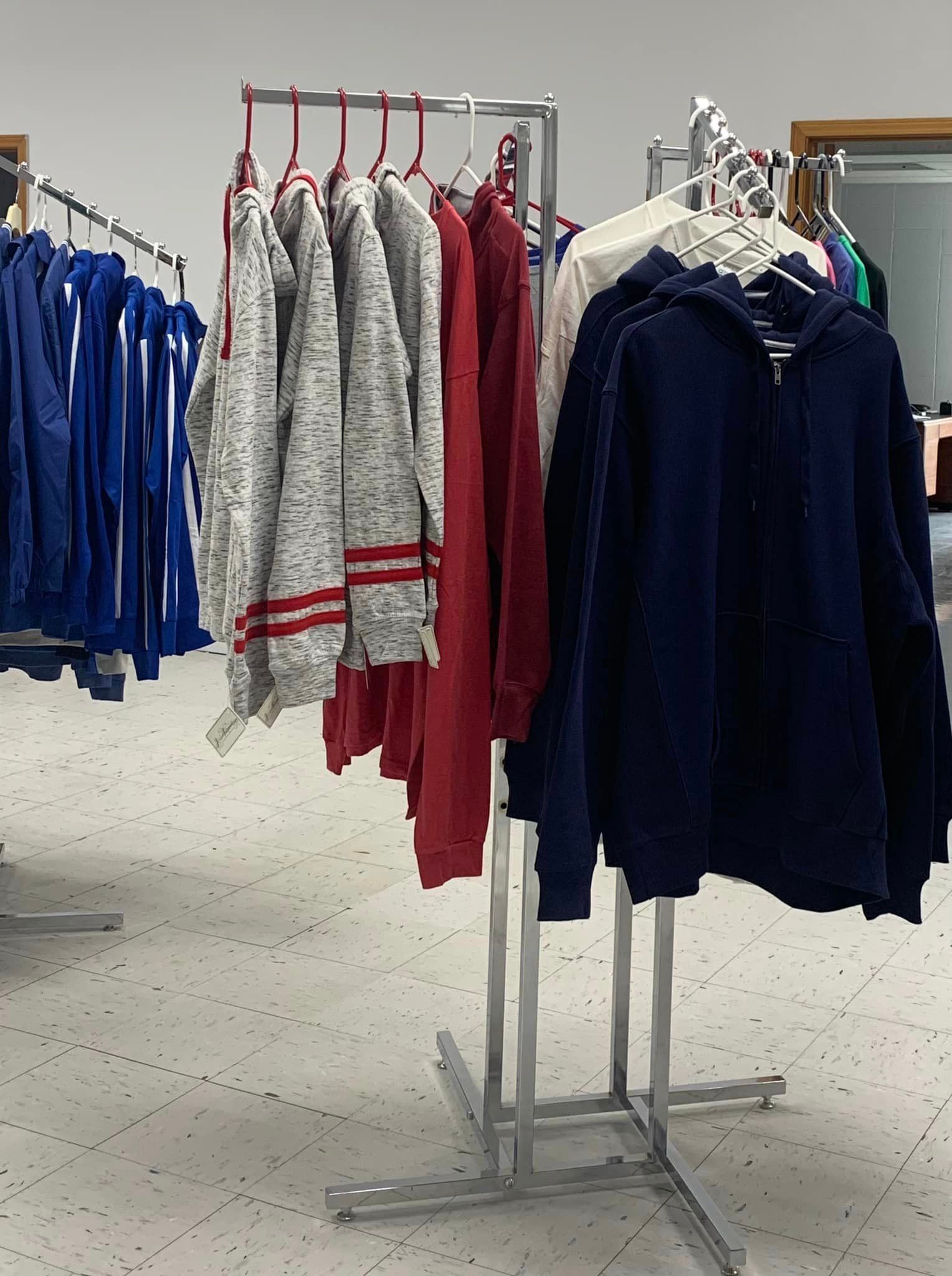Clothing racks with hanging sweaters and coats in a retail store.