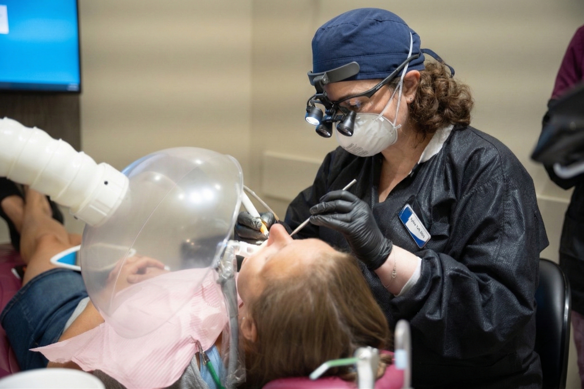 A dentist is examining a patient 's teeth in a dental office.
