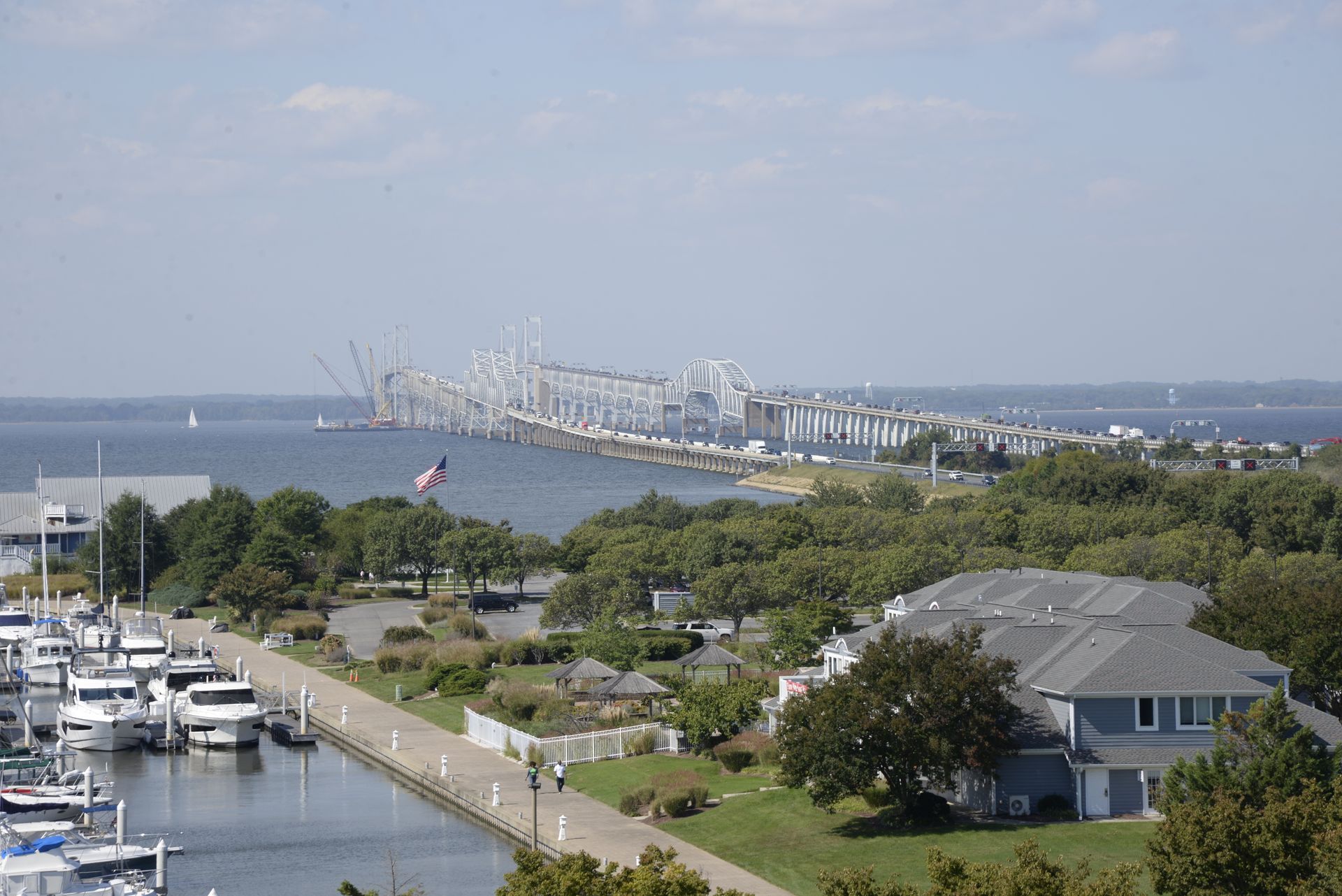 A view of the Chesapeake Bay Bridge spanning the water, with a marina and waterfront homes in the foreground.