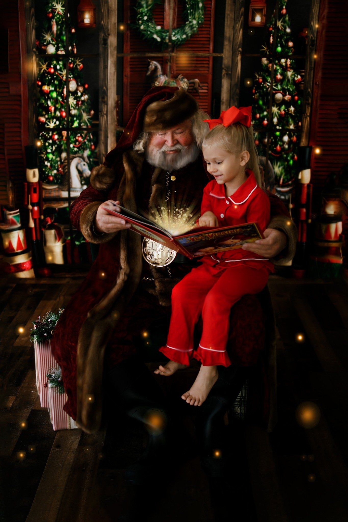 A little girl is sitting on santa 's lap reading a book.