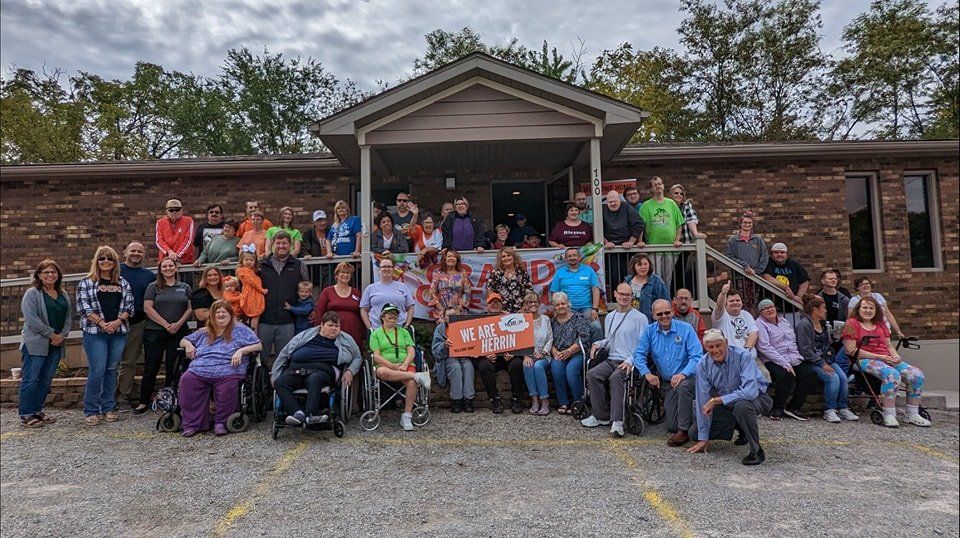 A large group of people are posing for a picture in front of a house.