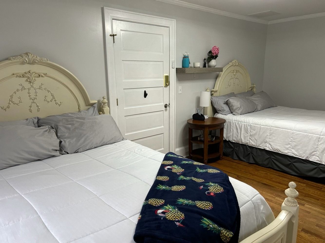 A bedroom with two beds and a nightstand.