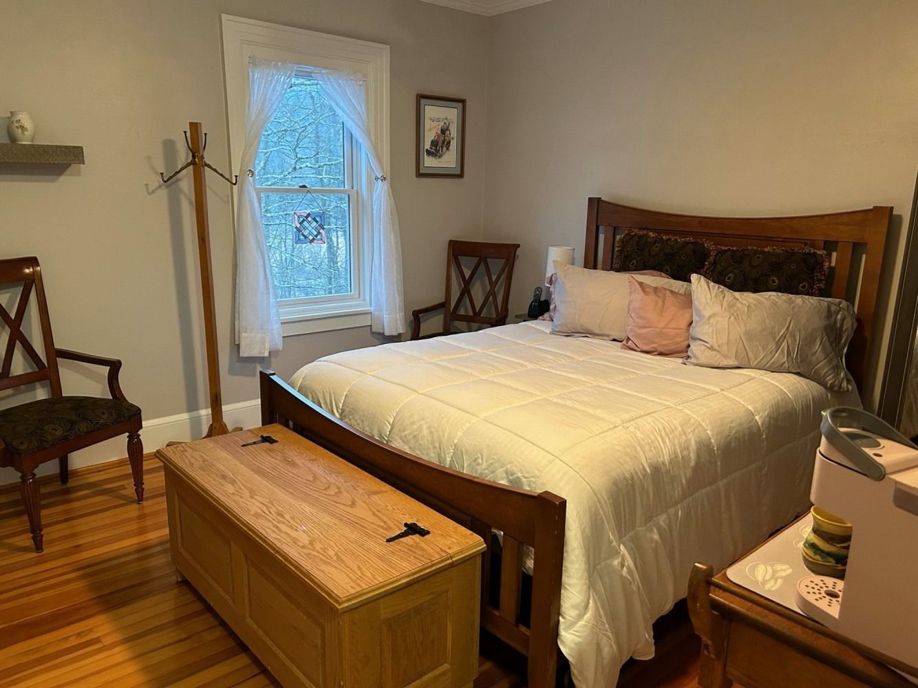 A bedroom with a bed , chair , dresser , and window.
